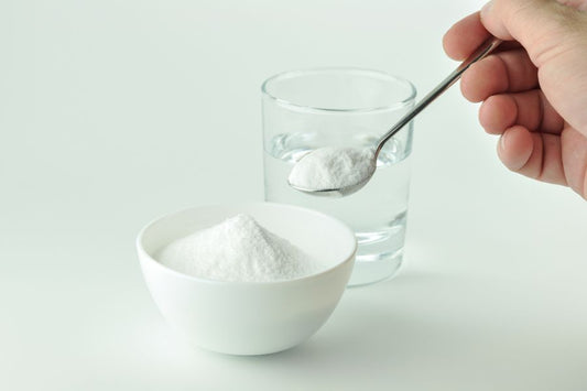 A spoonful of powder in a bowl and a glass of water