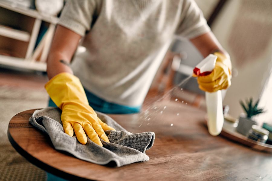 A person wearing gloves cleaning a table