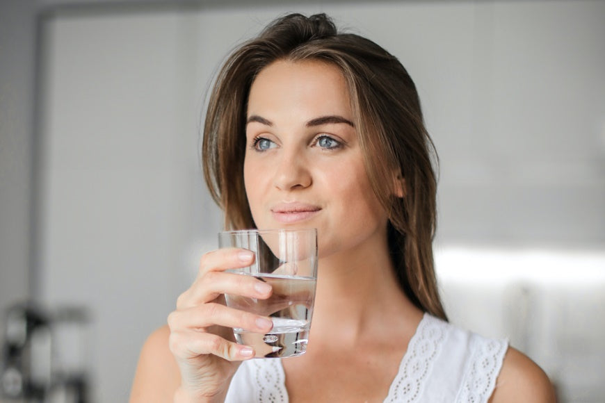 A young woman holding a glass of alkaline water