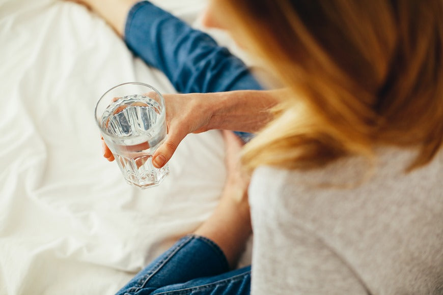 Woman sitting and holding a glass of alkaline water